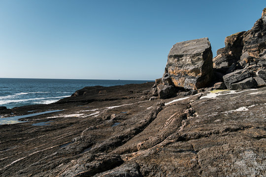 Rocky clifss with textured ground and white lines close to sea in Asturian Coast, Spain