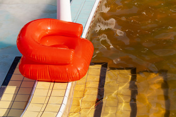 Red inflatable chair at a thermal pool with gold color water