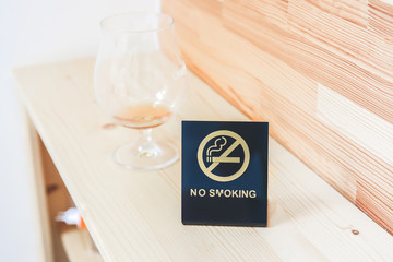 No smoking sign on the bedside table. Empty glass from drinks. Morning at the hotel.