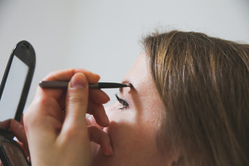 Girl is applying makeup. Eyebrows powder with brush. Beauty photo concept.