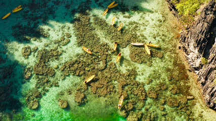 Tourists on the kayak in the lagoon with clear water, aerial view. Snorkeling and kayaking in the lagoon. Small lagoon with turquoise water. El nido, Philippines, Palawan. Summer and travel vacation