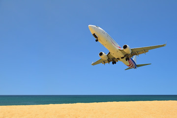 Fototapeta na wymiar Commercial plane landing at phuket on blue sky background, travel concept and business transportation idea