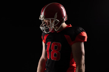 American football player in helmet standing against black background