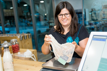 Happy female customer at cashier desk preparing to pay for her picking.