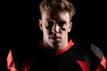 American football player standing against black background