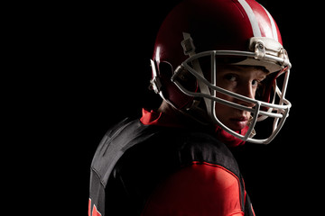 American football player in helmet standing against black background