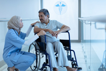 Female doctor interacting with disabled male patient in the corridor