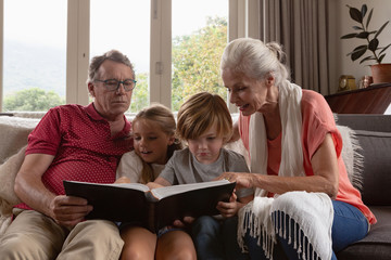 Multi-generation family looking at photo album on sofa in a comfortable home