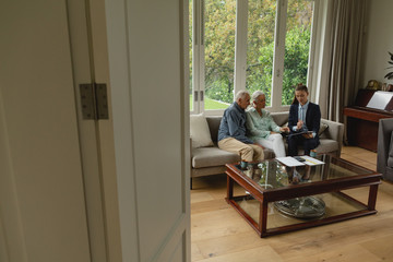 Active senior couple discussing with real estate agent over documents in living room