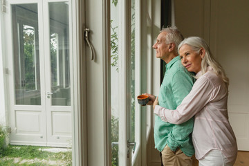 Active senior woman embracing senior man near door