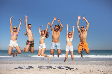 Group of friends jumping together on the beach