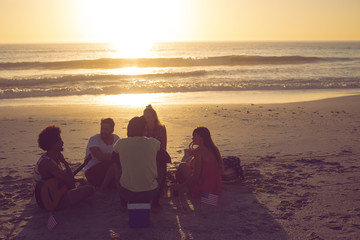 Group of friends having fun at beach during sunset