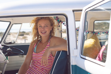 Woman looking at camera while sitting in camper van at beach