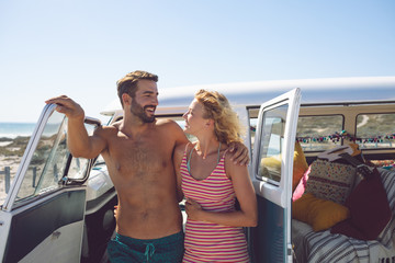 Couple talking with each other near camper van at beach in the sunshine