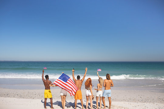 Group of friends raising their hands on the beach - Powered by Adobe