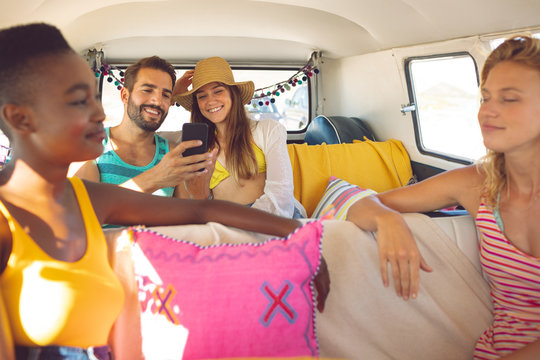 Group of friends having fun in a camper van at beach