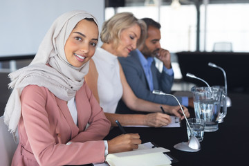 Fototapeta premium Businesswoman in hijab looking at camera at table in conference