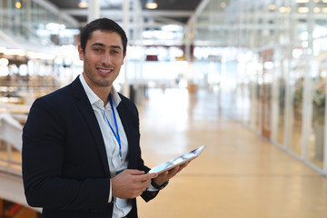 Businessman looking at camera while working on digital tablet in a modern office