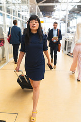 Fototapeta premium Businesswoman walking with luggage in corridor at office