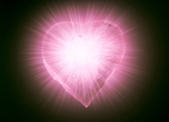 Ice frozen heart symbol of soft pink color close-up glowing in the dark. Texture of ice with bubbles.