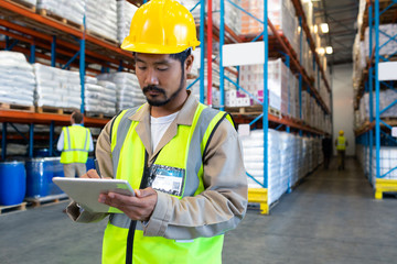 Male worker working on digital tablet in warehouse
