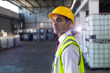 Fototapeta na wymiar Male staff in hardhat and reflective jacket standing in warehouse