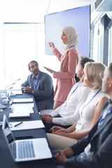 Businesswoman giving presentation at table in business seminar