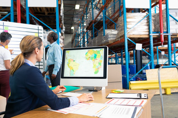 Female manager working on computer at desk in warehouse