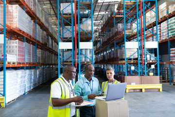 Warehouse staffs discussing over laptop in warehouse