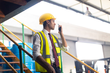 Male supervisor talking on walkie talkie on stairs