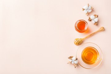 Cup of tea with honey on pastel pink, apricot background