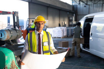 Male supervisor looking at blueprint in warehouse