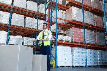 Male staff using pallet jack in warehouse