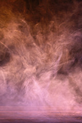 Conceptual image of multi-colored smoke isolated on dark black background and wooden table.