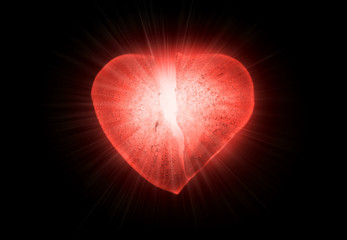 Ice frozen broken in half heart symbol of a bright red color close-up glowing in the darkness. Texture of ice with bubbles. Symbol of a broken heart. Allegory of unhappy love.