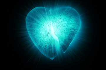 Ice frozen broken in half heart symbol of blue color close-up glowing in the dark in blue cold light. Texture of ice with bubbles. Symbol of a broken heart. Allegory of unhappy love.