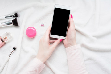 Women's hands, girl holding white smartphone, makeup brushes, phone screen, close up, copy space