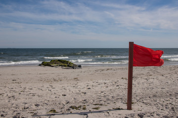 Warning sign of a red flag at a beautiful beach with a blue sky , Long Beach, New York, USA