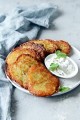 Crispy potato pancakes with green salad and yogurt sauce. Stack of potato fritters
