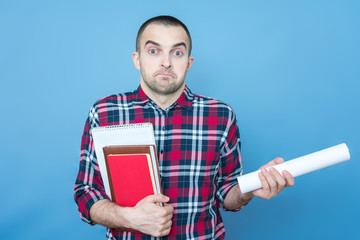 Loser or student with books, pursed lips, apologetic, blue background, copy space