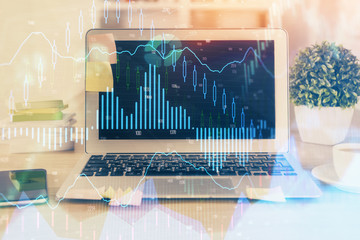 Double exposure of graph and financial info and work space with computer background. Concept of international online trading.