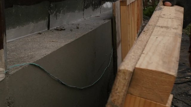 worker dismantles the wooden formwork, new foundation for old house. 4K