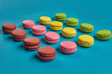 Colored macaron or macaroon, sweet meringue-based confection on blue background. Close-up, copy space.