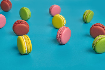 Colored macaron or macaroon, sweet meringue-based confection on blue background. Close-up, copy space.