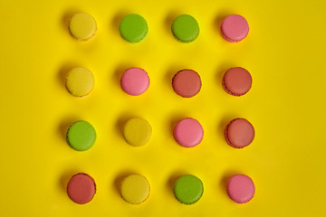 Colored macaron or macaroon, sweet meringue-based confection on yellow background. Close-up, copy space.