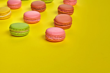 Colored macaron or macaroon, sweet meringue-based confection on yellow background. Close-up, copy space.