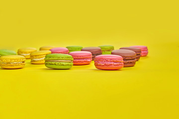 Colored macaron or macaroon, sweet meringue-based confection on yellow background. Close-up, copy space.