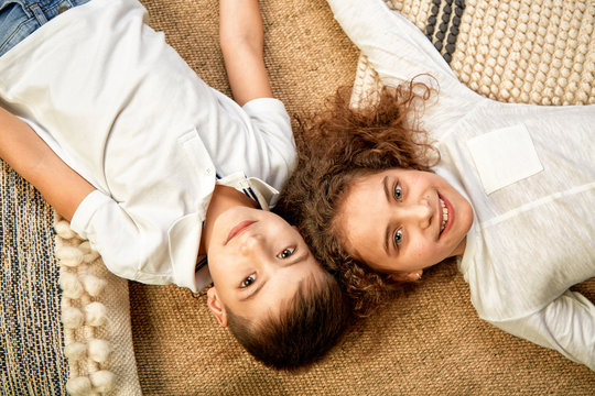 Beautiful children a boy and a girl lie on the floor and look at the camera. The concept of happiness, friendship of children. Children are lying on the floor with their heads touching and smiling.