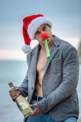 Obraz premium Man in Santa Claus red hat on the beach in morning hangover.