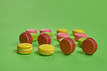 Colored macaron or macaroon, sweet meringue-based confection on green background. Close-up, copy space.